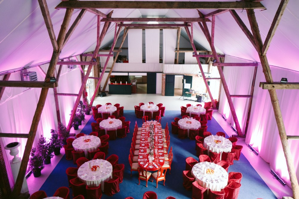 hochzeitsfeier im pinken Raum mit neun tischen mit catering