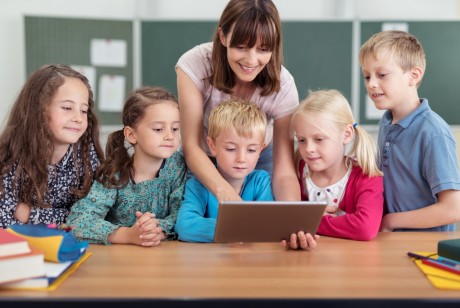 Kinder und eine Lehrerin schauen auf einen Block, politik, jugend